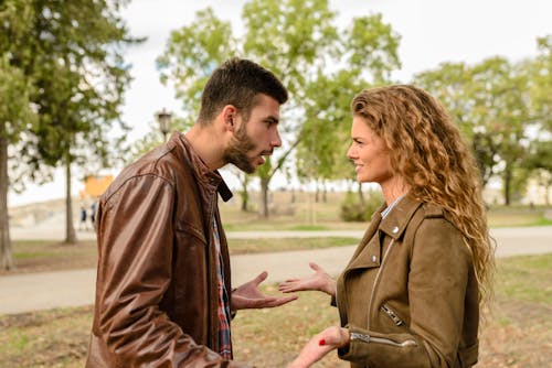 A woman calmly listens and gestures while a man speaks animatedly, demonstrating the concept of verbal passive resistance by being receptive yet rooted in her position.